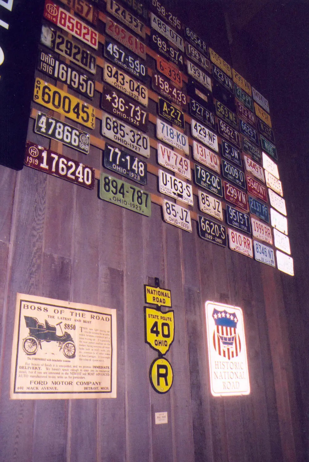 A wall of old Ohio license plates above National Road signs